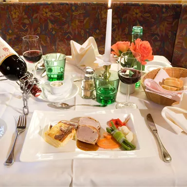 An elegantly set table with fine food, wine, and candlelight. The scene exudes a cozy atmosphere.