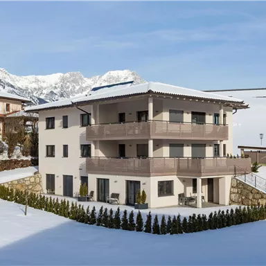 A modern house in the snow with a view of the mountains. The surroundings are quiet and idyllic.