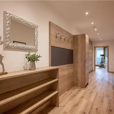 A bright corridor with wooden flooring and modern design. An elegant wall mirror and a stylish decoration in the shape of a reindeer give the room character.
