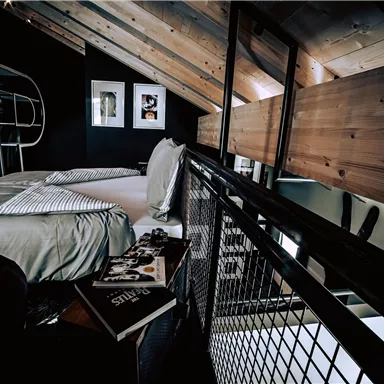 A modern bedroom with a wooden ceiling and minimalist decor. The atmosphere is cozy and inviting.
