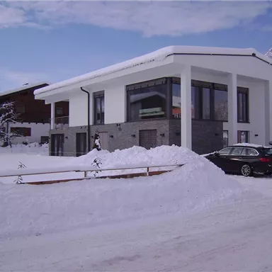 Ein modernes Haus in einer verschneiten Landschaft. Die Umgebung ist ruhig und winterlich.