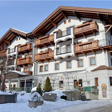 Eine beeindruckende Berghütte im Schnee mit traditionellen Holzbalkonen. Die Umgebung ist winterlich und einladend.