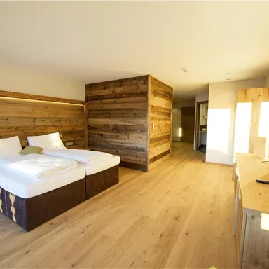 Ein modernes Hotelzimmer mit Holzdetails und zwei Betten. Der Raum ist hell und freundlich gestaltet, mit einem großen Fenster und minimalistischem Mobiliar.
