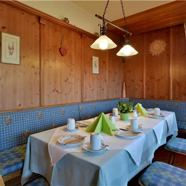 Ein einladender Essbereich mit Holzverkleidung und einer gemütlichen Atmosphäre. Der Tisch ist gedeckt mit Tellern und grünen Servietten.