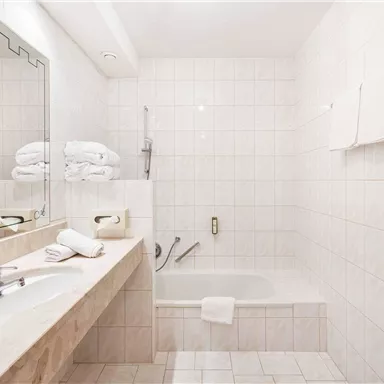 Fresh into the day: The bright bathroom with a generous mirror, double washbasin, and bathtub ensures a sense of well-being and comfort.