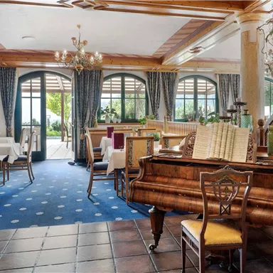 A Touch of Nostalgia: The elegant dining room with a grand piano and stylish decor ensures enjoyable evenings in a special atmosphere.