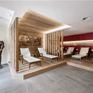 A modern relaxation room with comfortable loungers and warm wooden elements. A knight statue is also visible, giving the room a unique character.