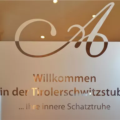 A glass front with the inscription "Welcome to the Tyrolean Sweat Room". The invitation emphasizes that it is an "inner treasure chest".