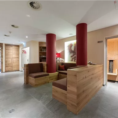 A modern wellness area with wooden paneling and comfortable seating. In the background, a sauna is visible, inviting relaxation.