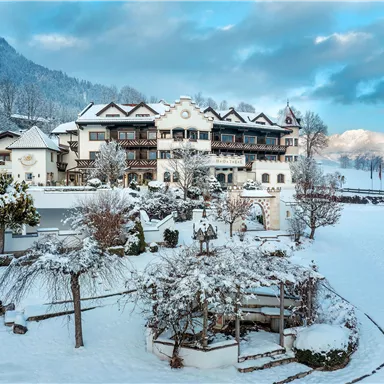A picturesque hotel in a snow-covered landscape. The surroundings are idyllic, with snow-covered trees and gentle hills in the background.