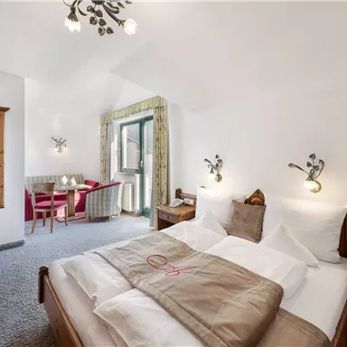 A cozy hotel room with a double bed and modern decor. A table with chairs and a large mirror complement the space.