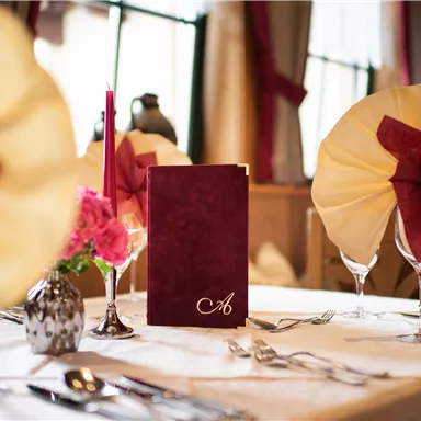 An elegantly set table with a menu and stylish napkins. The decoration includes flowers and candles that create a cozy atmosphere.