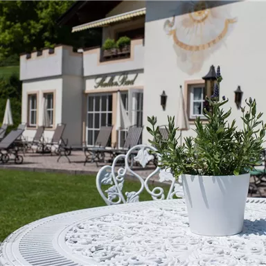 A beautiful outdoor area with loungers and sun umbrellas. In the foreground is a table with a flower pot.