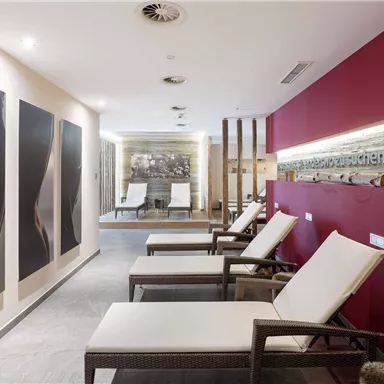 An elegant wellness area with comfortable loungers and modern artworks on the walls. Soft lighting creates a relaxing atmosphere.