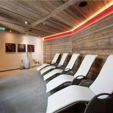 A tranquil wellness area with modern loungers and wood paneling. Soft lighting creates a relaxing atmosphere.