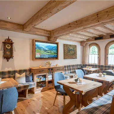 Ein gemütliches Restaurant mit Holzmöbeln und einem rustikalen Ambiente. Große Fenster sorgen für viel Tageslicht und eine einladende Atmosphäre.