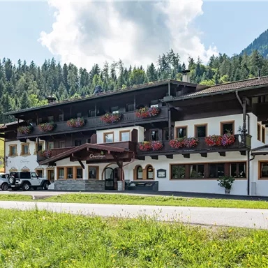 Ein charmantes Hotel im alpinen Stil mit blühenden Balkonen. Umgeben von grünen Wiesen und majestätischen Bergen.