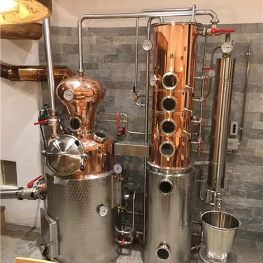 An elegant distillation pot made of copper and stainless steel stands in a modern room. The setup is equipped with various pipes and instruments.