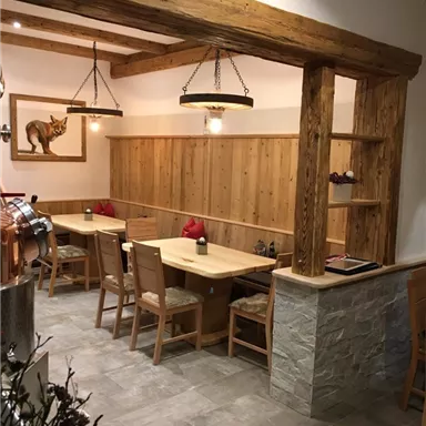 A cozy restaurant with wooden decor. There are tables and chairs as well as a warm atmosphere.