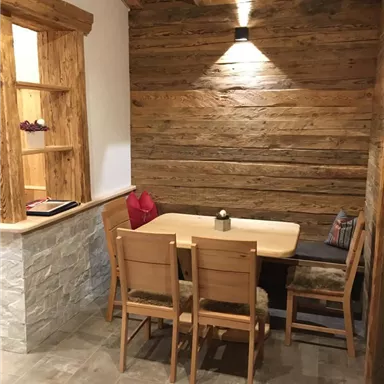 A cozy dining area with a wooden table and chairs. The walls are made of wood, and there is soft lighting.