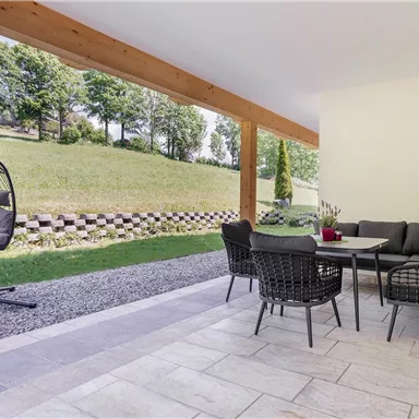 Perfect for any time of day: The terrace of the Steintal Suite offers comfort with a hanging chair, outdoor dining area, and views of nature.