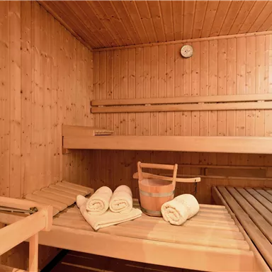 Eine gemütliche Sauna mit Holzverkleidung. Handtücher und ein Saunabereich sind bereit für Entspannung.