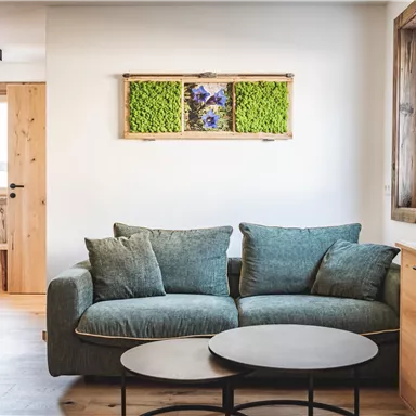 A modern living room with a comfortable sofa and a round coffee table. Wooden elements and plants create a cozy atmosphere.