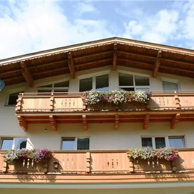 An alpine-inspired facade with wooden balconies and colorful flowers. The sky is clear and blue.