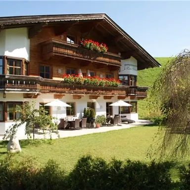 Ein charmantes skandinavisches Holzhaus mit blühenden Balkonen. Der grüne Garten und die sonnige Umgebung laden zum Entspannen ein.