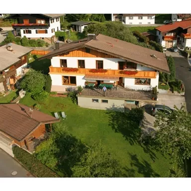 Ein schönes Haus mit Balkon und Garten in einer ruhigen Wohngegend. Umgeben von weiteren Häusern und viel Grün.