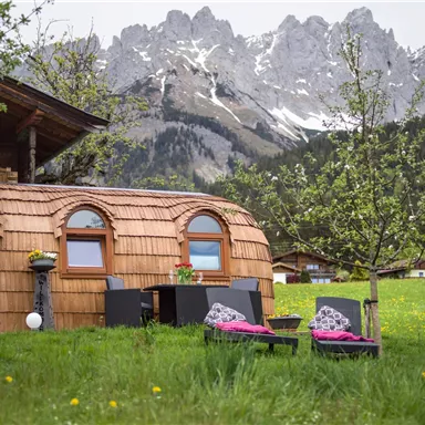 A cozy wooden house in a picturesque landscape. In the background, majestic snow-capped mountains can be seen.