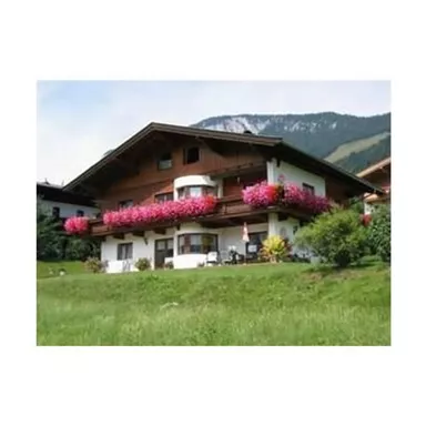 A cozy house with a large garden and colorful hanging flowers. In the background, gentle mountains can be seen.