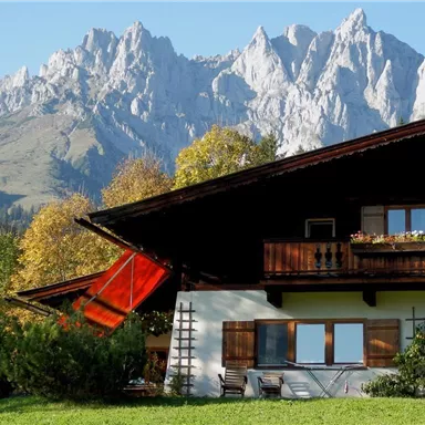 Ein malerisches Chalet vor imposanten Berggipfeln. Die Umgebung ist grün und einladend, ideal für einen Rückzugsort in der Natur.