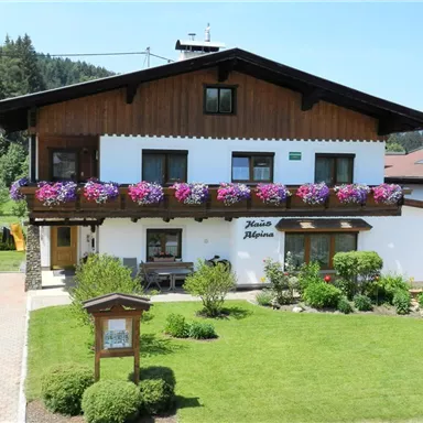 A charming house with a wooden porch and colorful flower boxes. The well-maintained garden creates an inviting atmosphere.