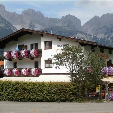 A traditional inn with colorful flower boxes. In the background, impressive mountains can be seen.