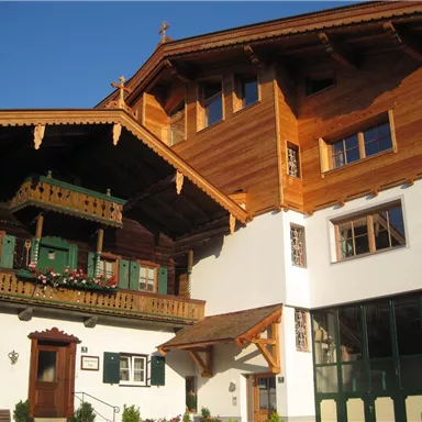 A traditional wooden house with a balcony and decorative windows. The architecture is typical for the Alpine region.