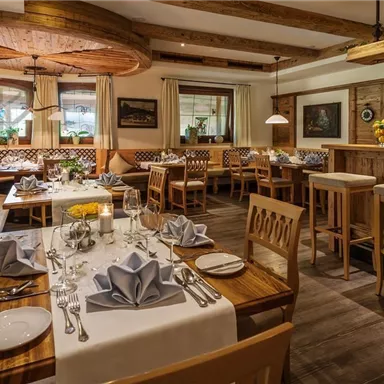 A cozy restaurant with wooden interiors and soft lighting. The tables are elegantly set and provide space for diners.