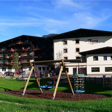 A hotel in Tyrol with beautiful architecture and an adjacent playground. The green lawn invites relaxation and play.