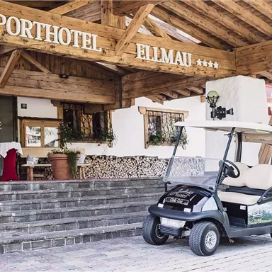 A sporty hotel with rustic wooden design. A golf cart is located in front of the entrance.
