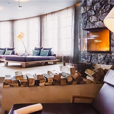 An inviting wellness area with comfortable loungers and large windows. The fireplace creates a relaxed atmosphere.