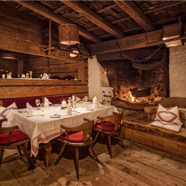 A cozy, rustic parlor with wooden furniture and a fireplace. The table is elegantly set and radiates an inviting atmosphere.