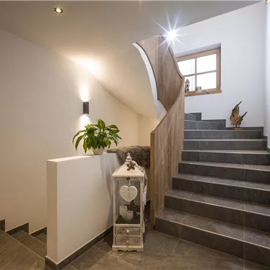 A bright stairway with modern design. The walls are white, and plants adorn the space.