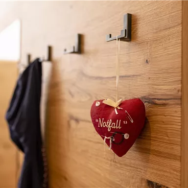 Ein hölzerner Wandhaken mit einem roten Herz als Dekoration. Das Herz trägt die Aufschrift "Notfall".