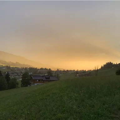 A picturesque landscape with gentle hills, green meadows, and a warm sunset. The scene radiates tranquility and a connection to nature.