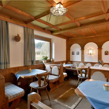 Ein gemütliches Restaurant mit Holzverkleidung und blauen Tischen. Die Wände sind mit kleinen Bildern und Fenstern ausgestattet, die einen Blick nach draußen ermöglichen.