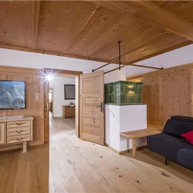 A cozy living space with wooden ceilings and a modern sofa. In the background, there is a television and an area with a small aquarium.