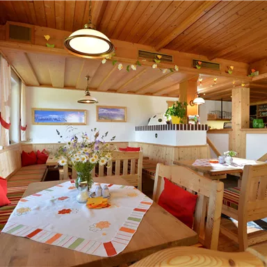 Ein einladendes Restaurant mit Holzinterieur und gemütlichen Sitzecken. Blumenarrangements auf den Tischen und ein freundlicher Schreibtischbereich schaffen eine warme Atmosphäre.