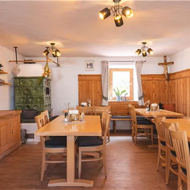 Ein gemütlicher Raum mit Holzmöbeln und warmem Licht. Es gibt Tische und eine Dekoration im ländlichen Stil.