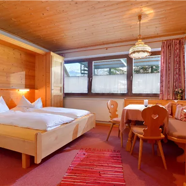 Ein gemütliches Schlafzimmer mit Holzvertäfelung und zwei Betten. Ein kleiner Essbereich mit Tisch und Stühlen ist ebenfalls vorhanden.