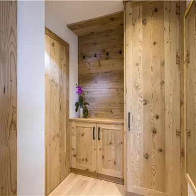 An inviting hallway with wood paneling and modern furniture. An orchid adds a friendly touch to the space.